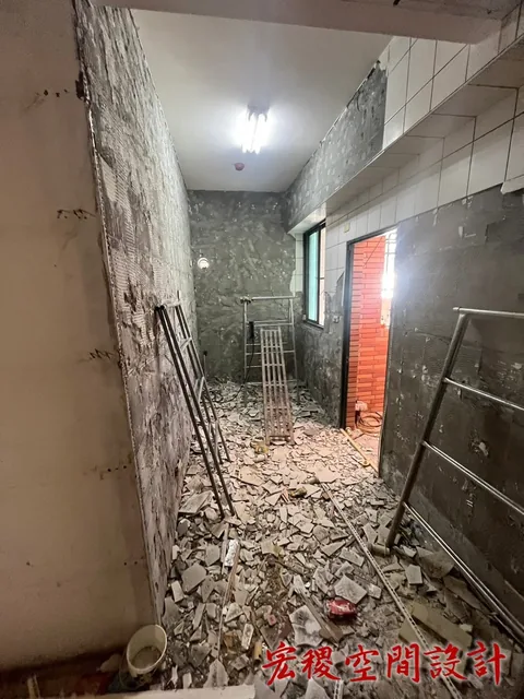 室內牆面拆除後裸露，地面可見磚石與工具。
