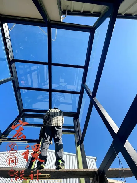 仰拍採光罩框架與施工人員的畫面。