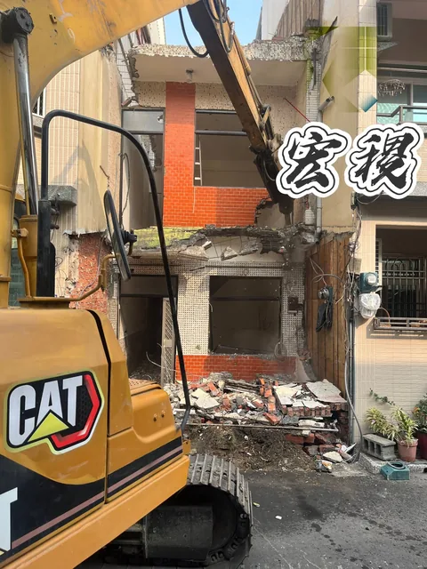 挖土機在街屋前作業，現場可見拆除碎料。