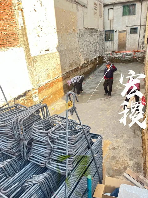 裸露牆面間的施工工區與堆放鋼筋。