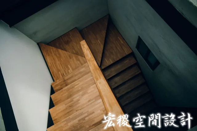 由上俯拍的木色轉折樓梯與扶手。
