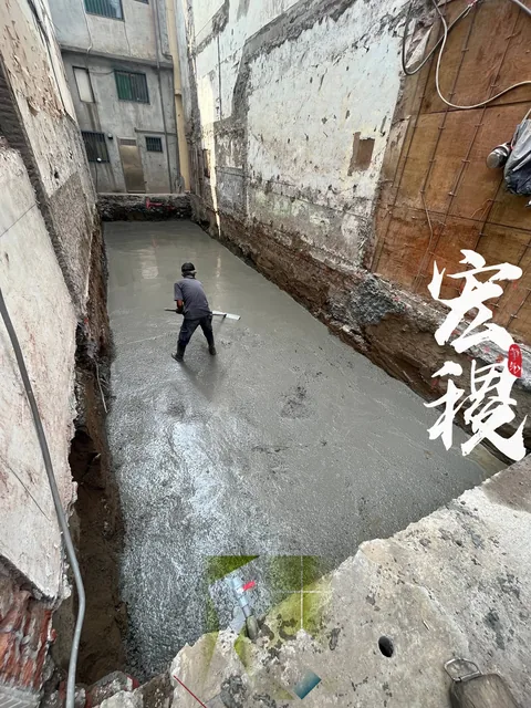 狹長工區中人員正在整平新鋪設的地坪。