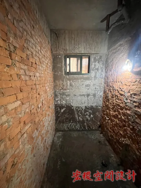 狹長室內空間的裸磚牆與拆除後地面。